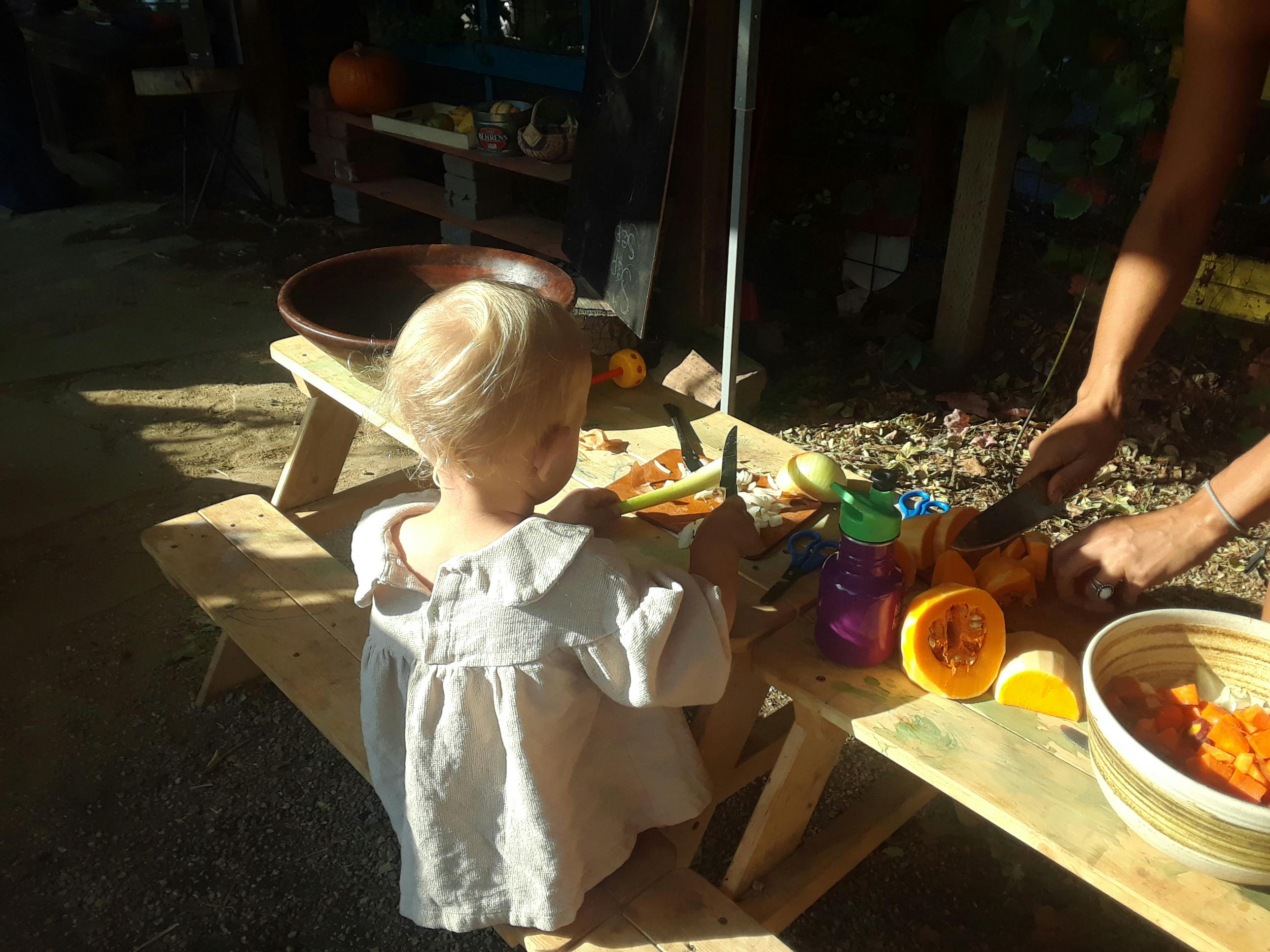 Child and person cutting fruit on a wooden table