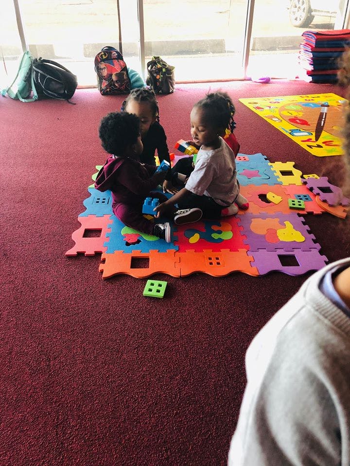 Three children playing with colorful puzzle mats on a red carpet