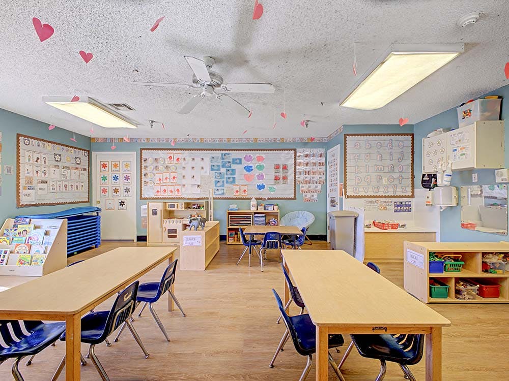 Classroom with child-sized tables and chairs, and bulletin boards with alphabet