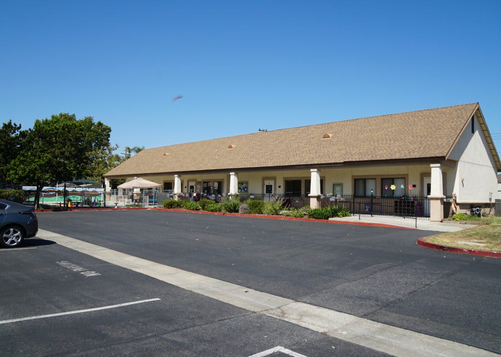 Long building with a brown roof and a parking lot in front