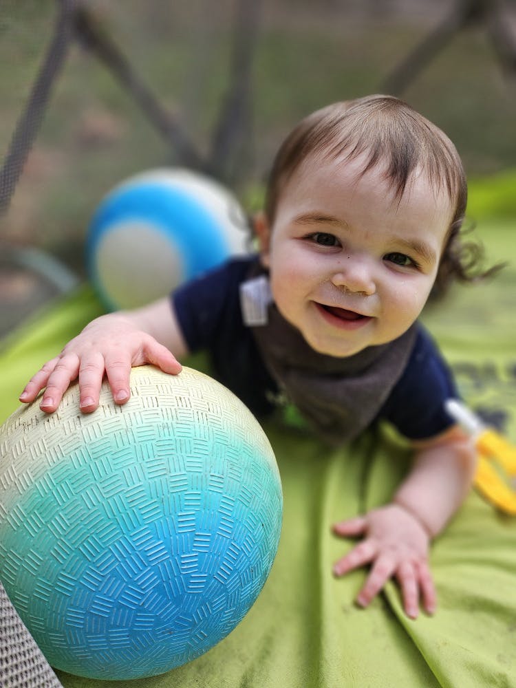 Child on stomach with hand on a ball