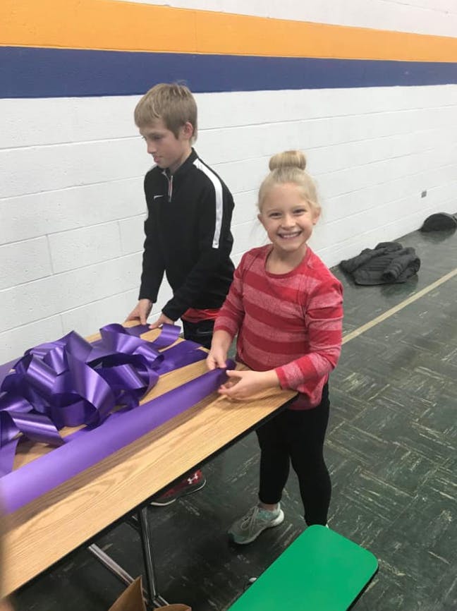 Two children working with purple ribbon on a table