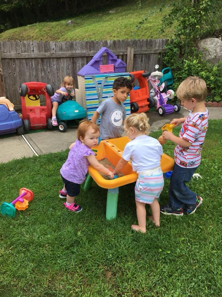 Children playing with toys in a grassy outdoor area