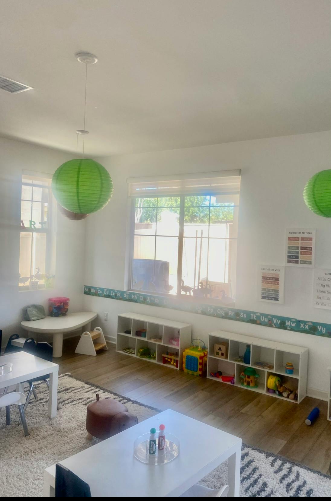 Classroom with small tables, toy shelves, and alphabet border