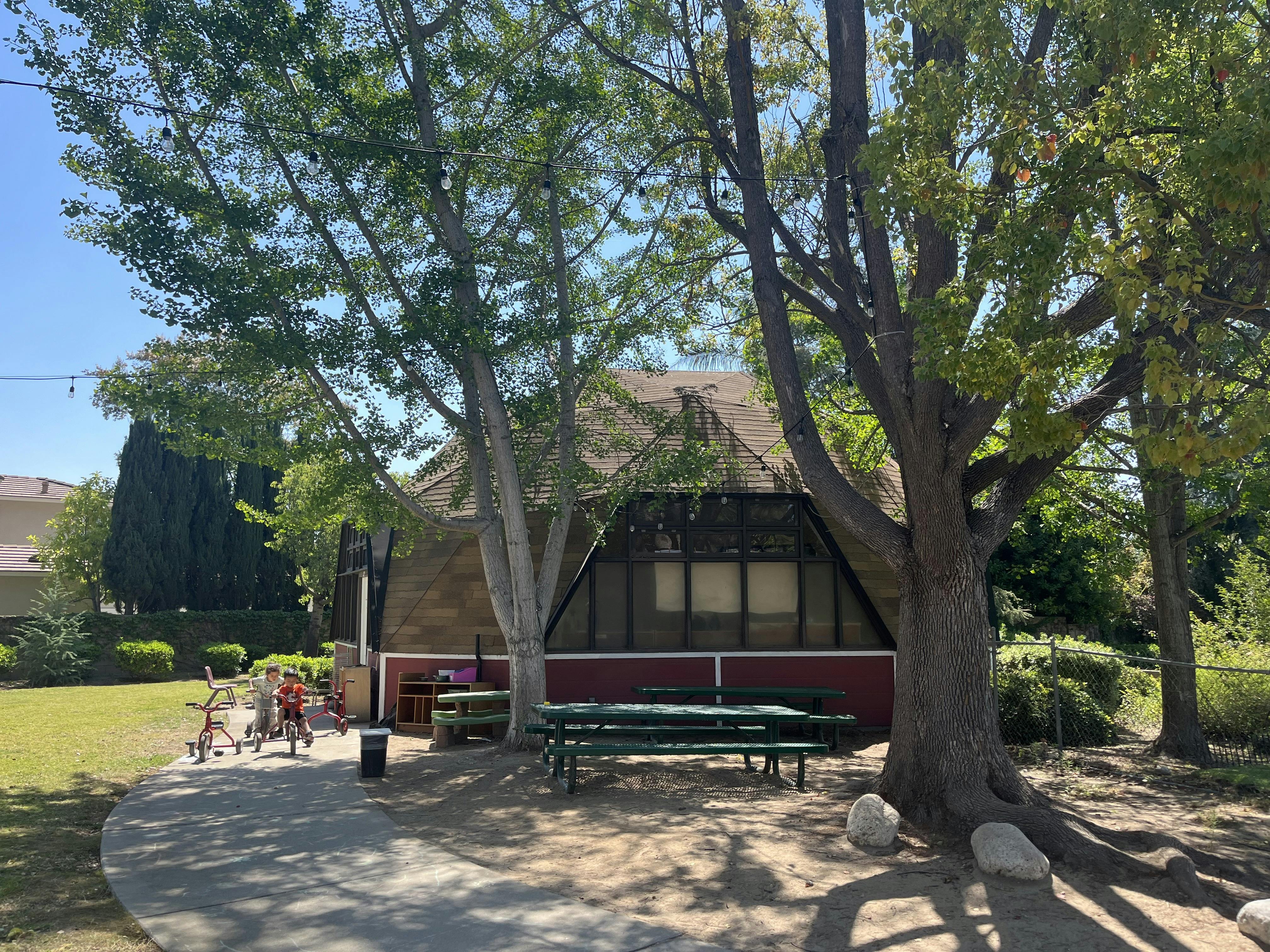 Children riding tricycles on a curved path next to a building
