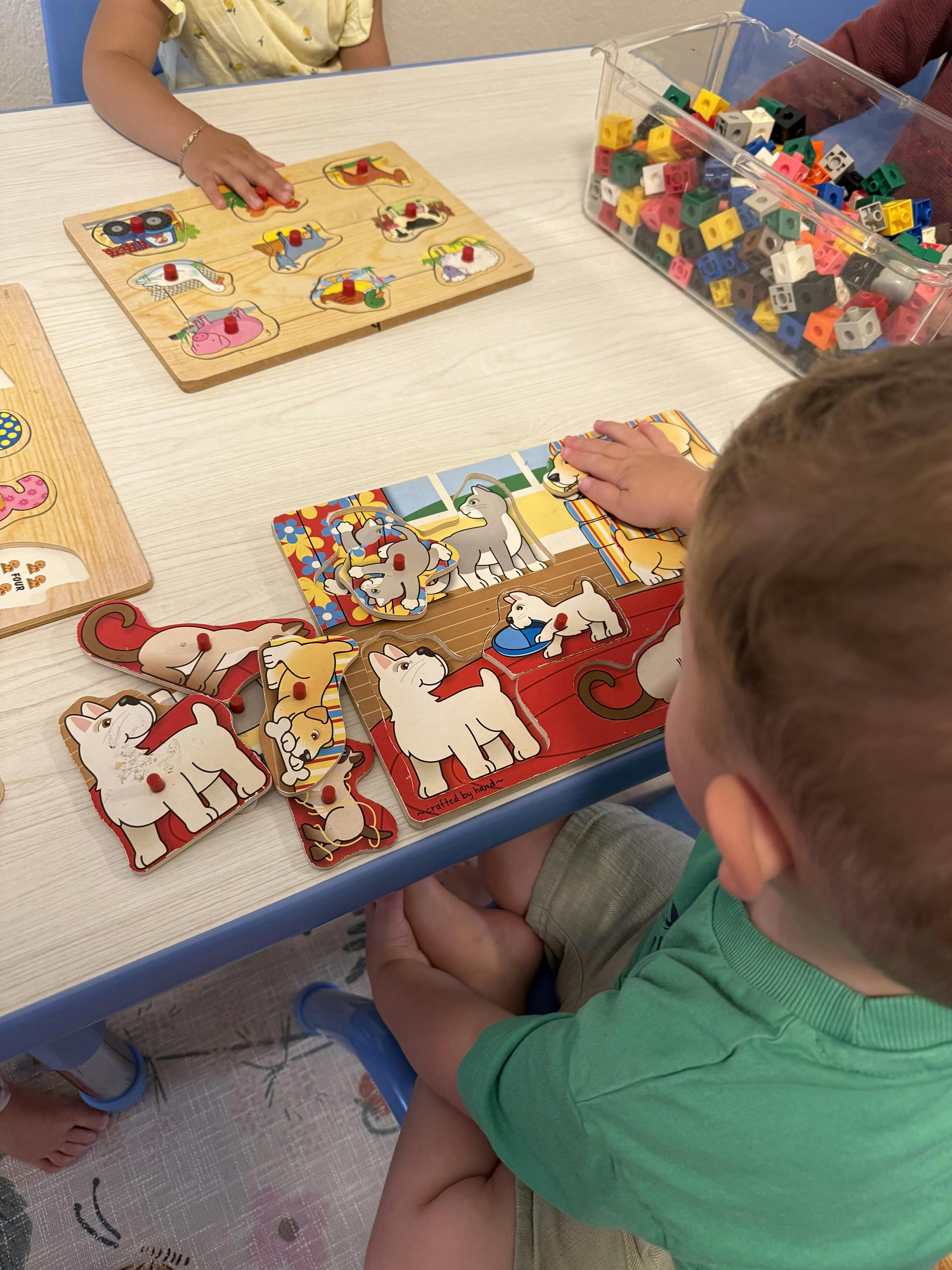 Children working on wooden animal puzzles at a table