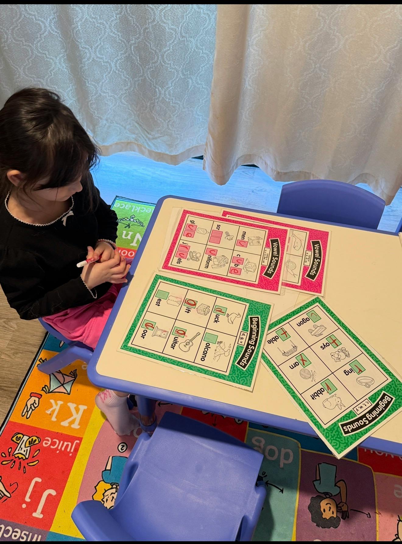 Child sitting at a table working on phonics activity worksheets