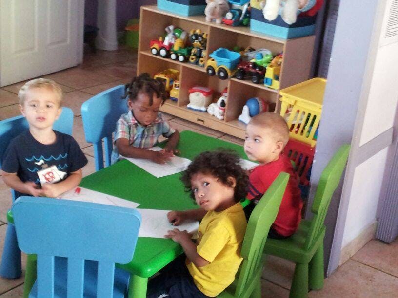 Four children sitting at a table with paper