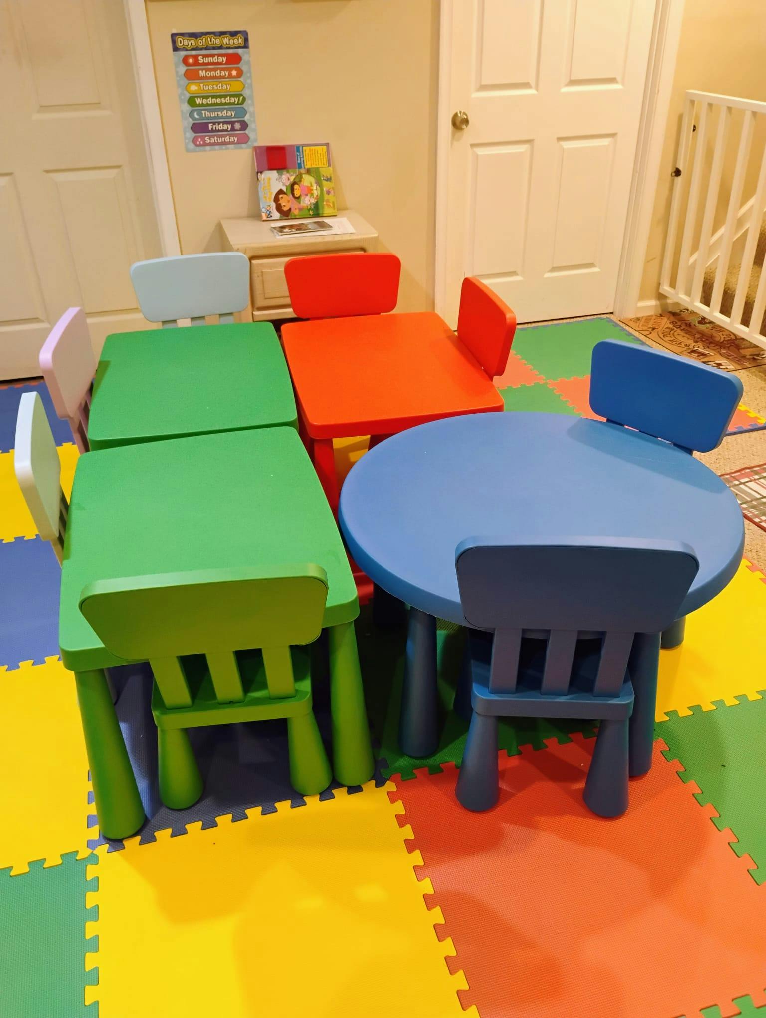 Small plastic tables and chairs on a colorful foam floor mat