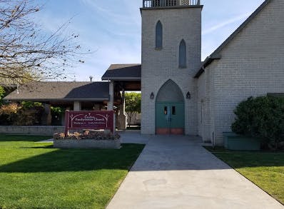Church building with a tall steeple and a sign in front