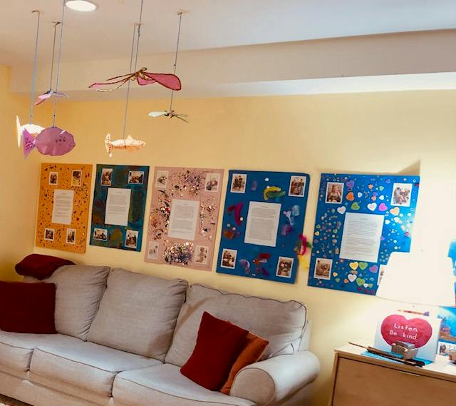Decorative poster boards and hanging paper fish above a living room sofa