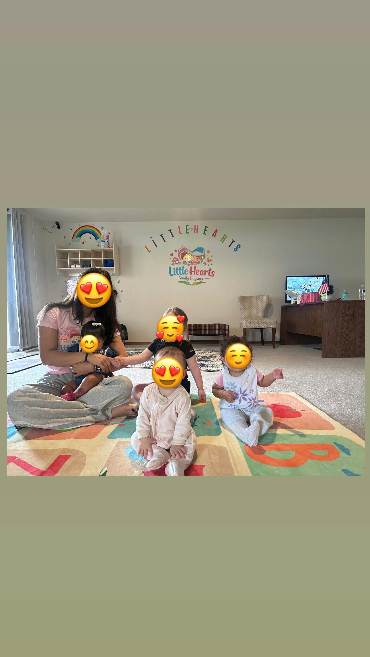 A person holding a child and three children sitting on a mat at a daycare