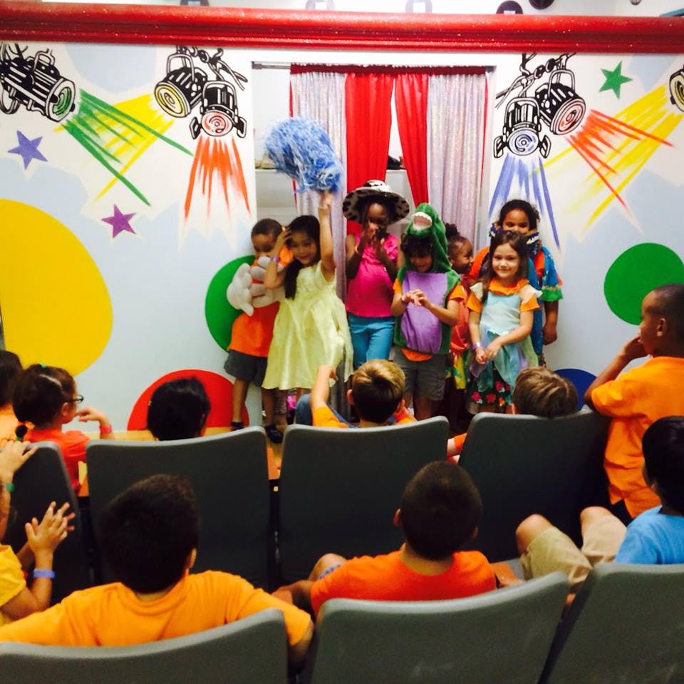 Children performing on a stage for an audience of children