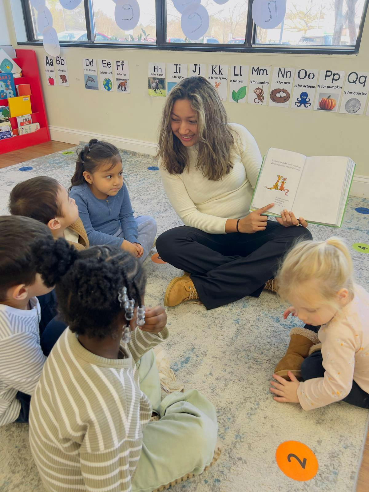 Person reading a book to a group of children in a classroom