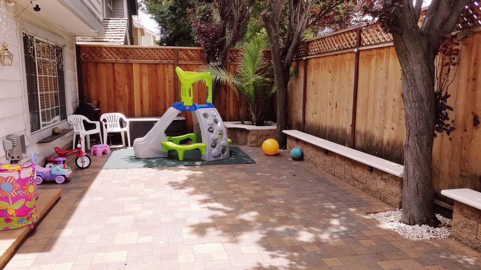 Backyard patio with a small slide and toys