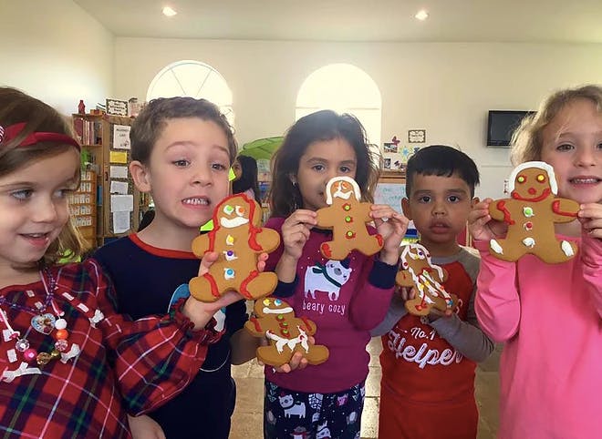 Group of children holding up gingerbread cookies
