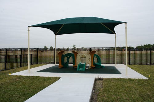 Playground with a green shade structure over play equipment