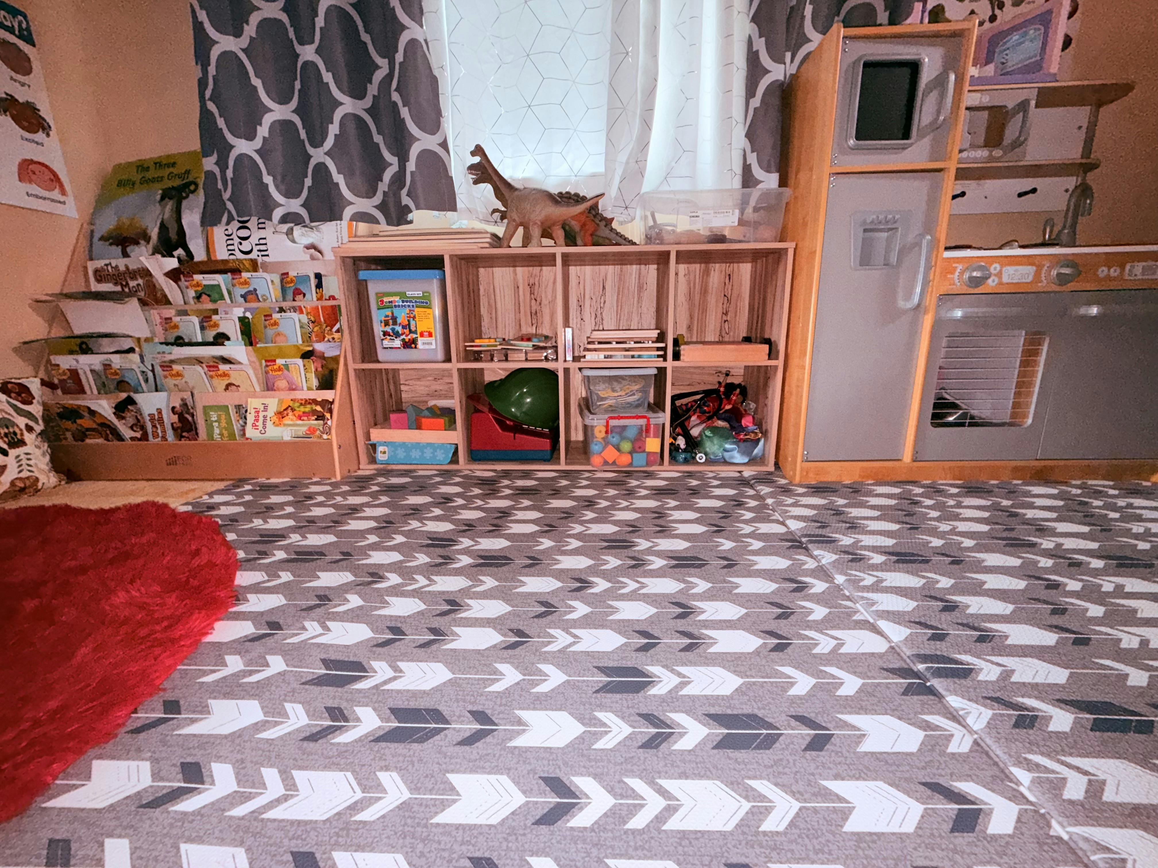 Playroom with toy kitchen, bookshelves, and patterned rug