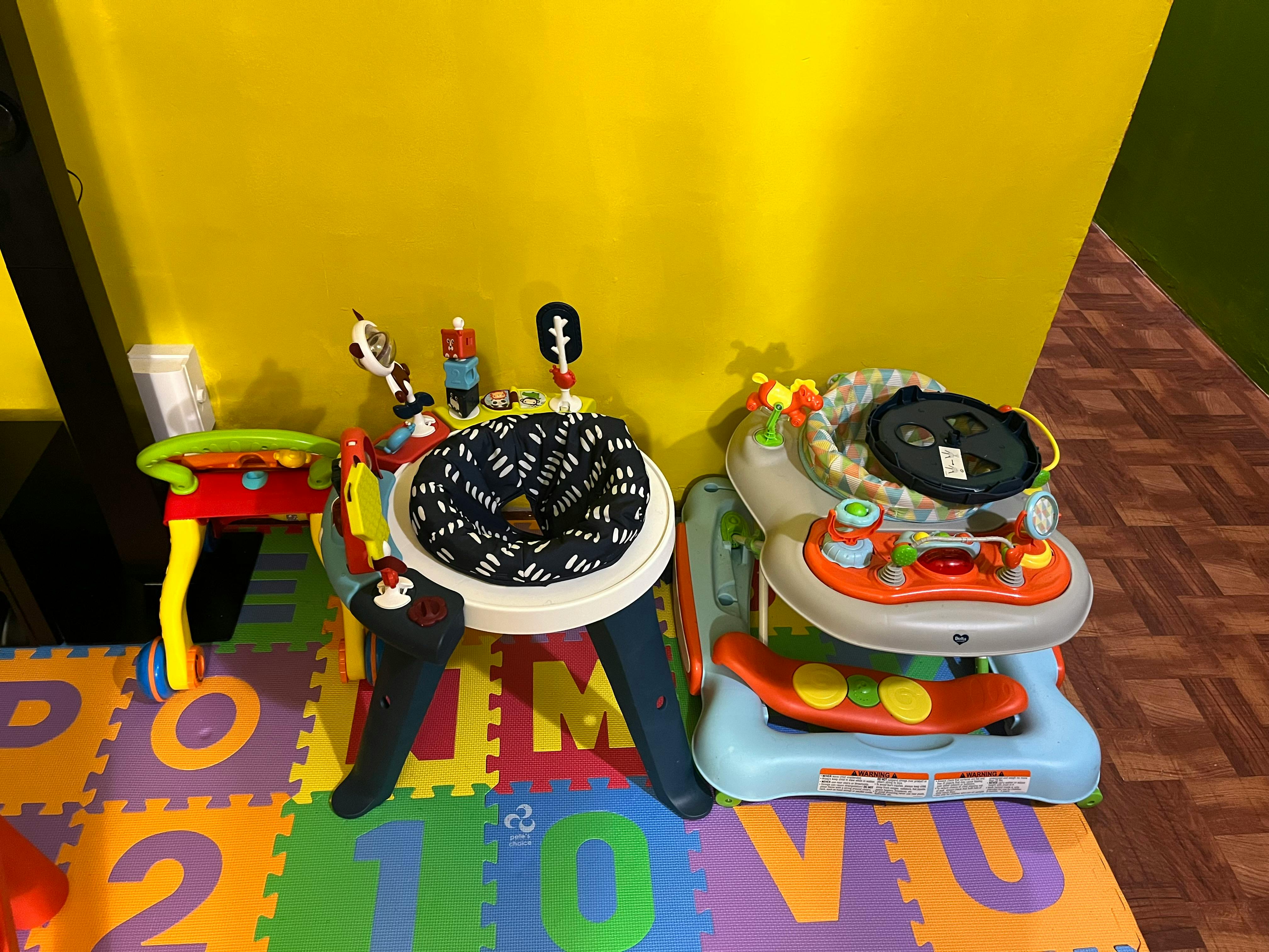 Baby activity centers and a toy drum on a colorful play mat