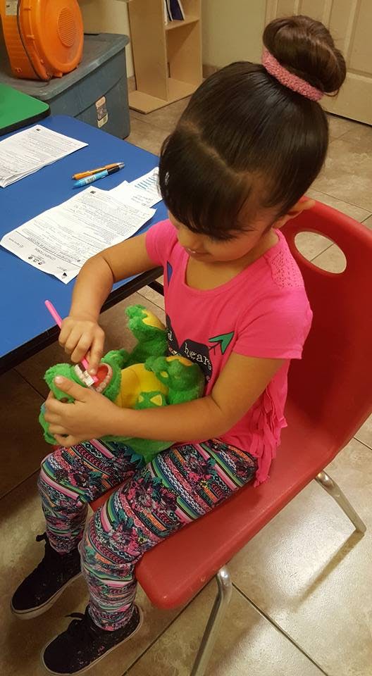 Child brushing the teeth of a stuffed animal