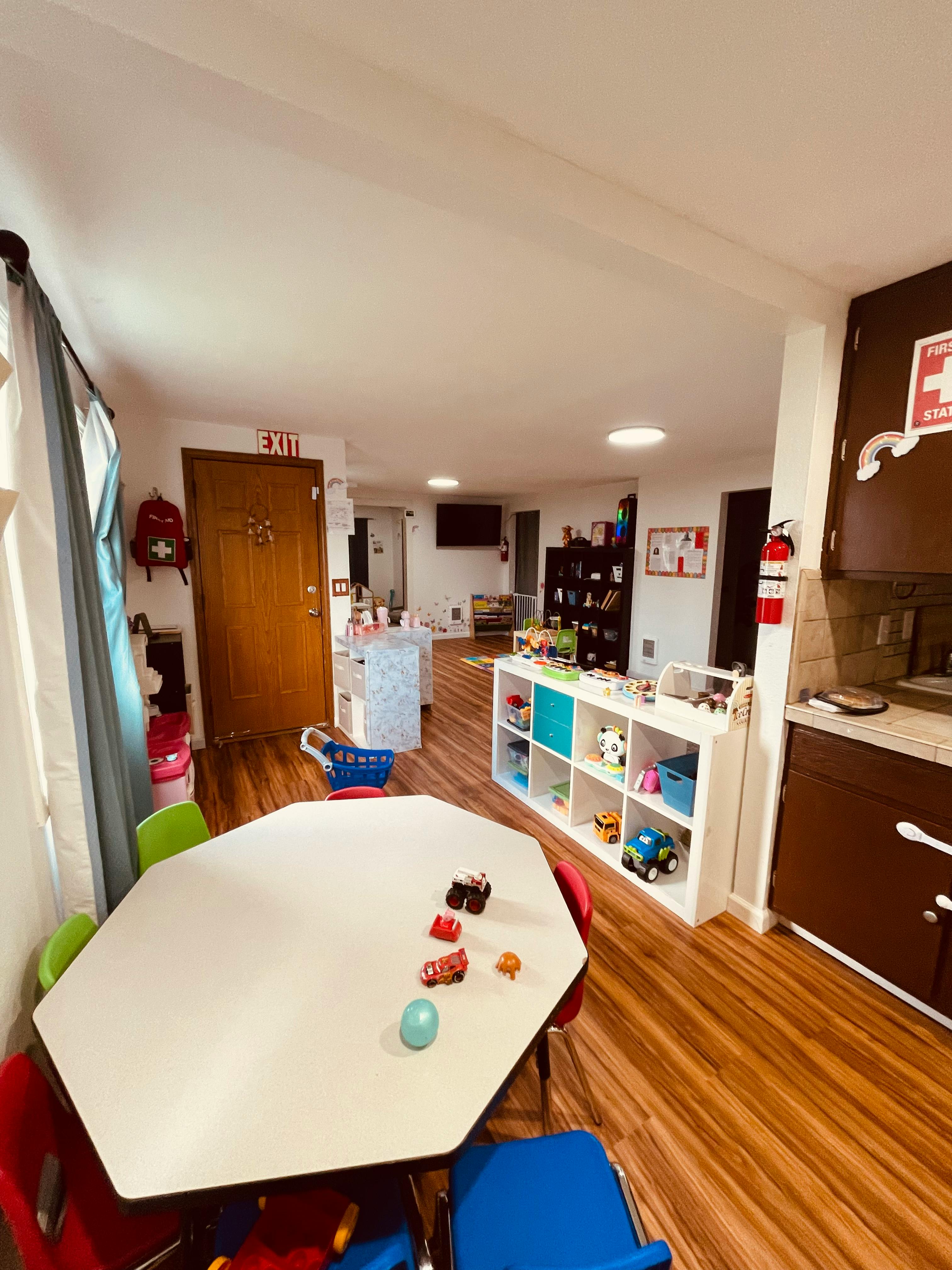 Playroom with a table and chairs, toy shelf, and wooden floor