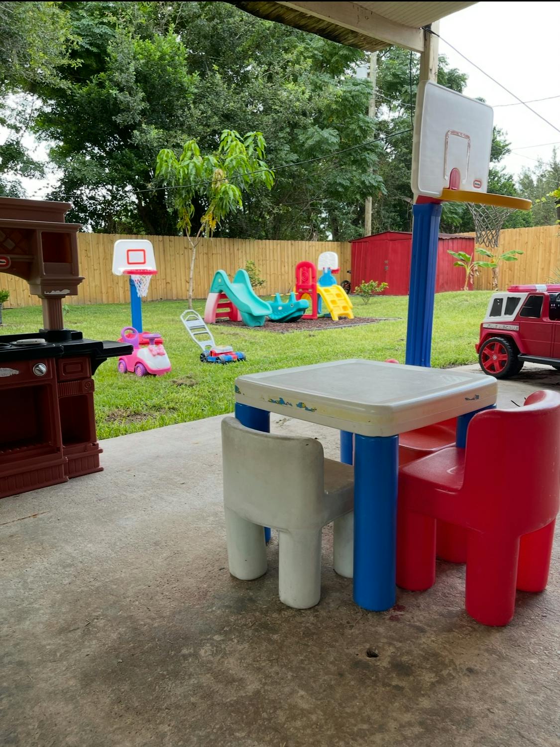Outdoor play area with a small table and chairs, slide, and toy vehicles