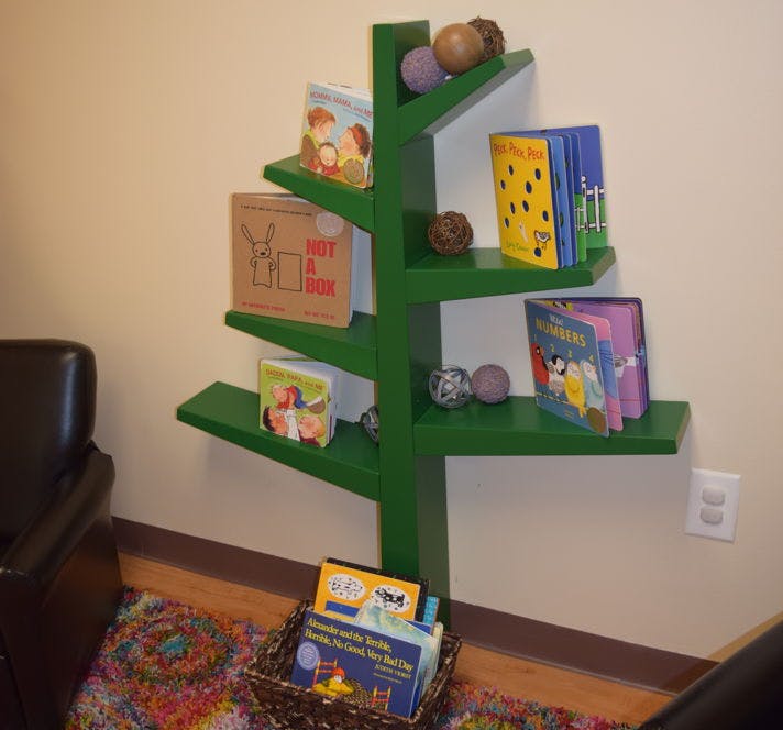 Green tree-shaped bookshelf with books and decorative spheres