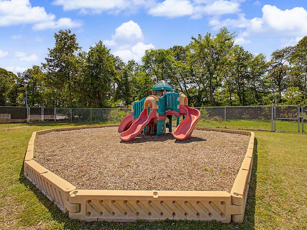 A colorful playground with multiple slides and a climbing structure on wood chips