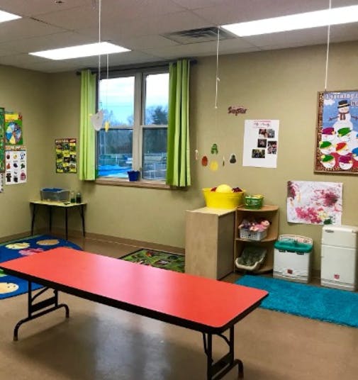 Classroom with a red table, green curtains, and colorful decorations