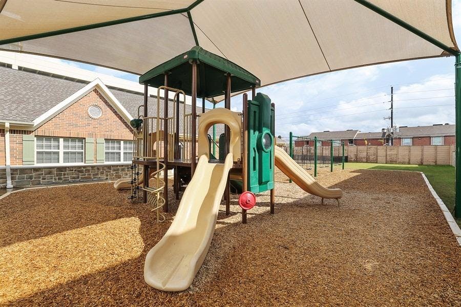 Playground with slides and climbing structure under a shade canopy