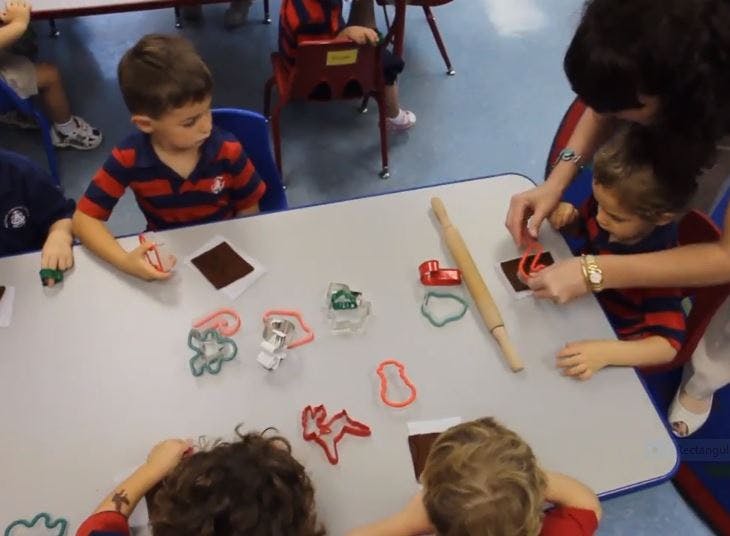 Adult and children using cookie cutters at a table