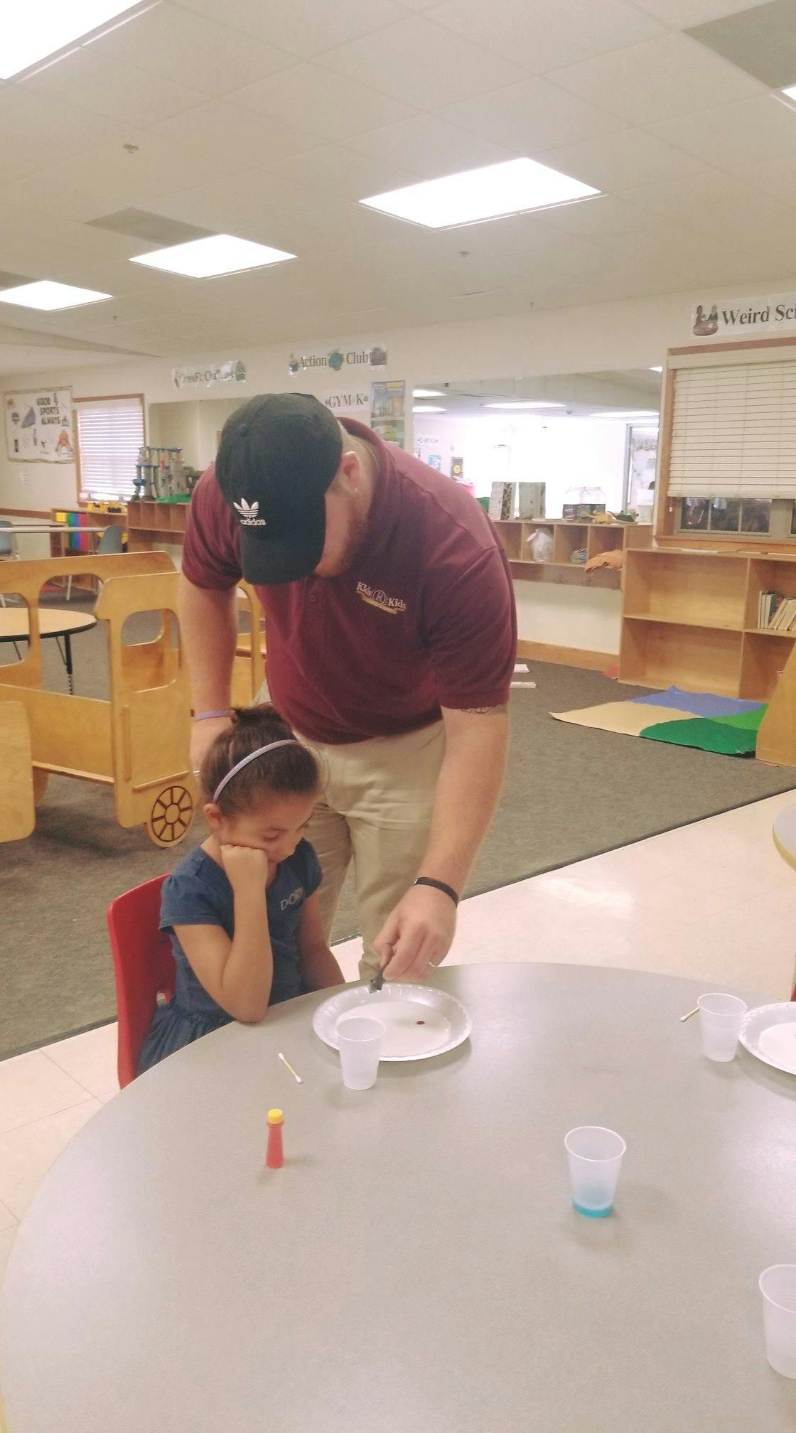 Adult and child at a table with craft supplies in a classroom