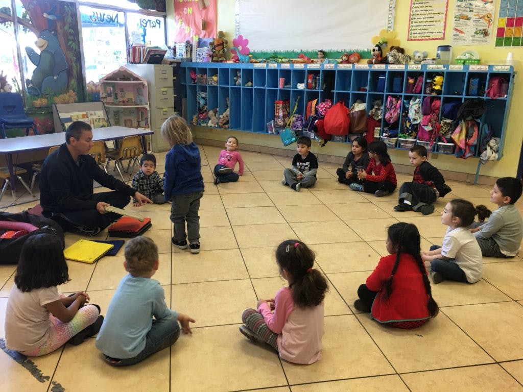 Adult and children sitting on the floor in a classroom