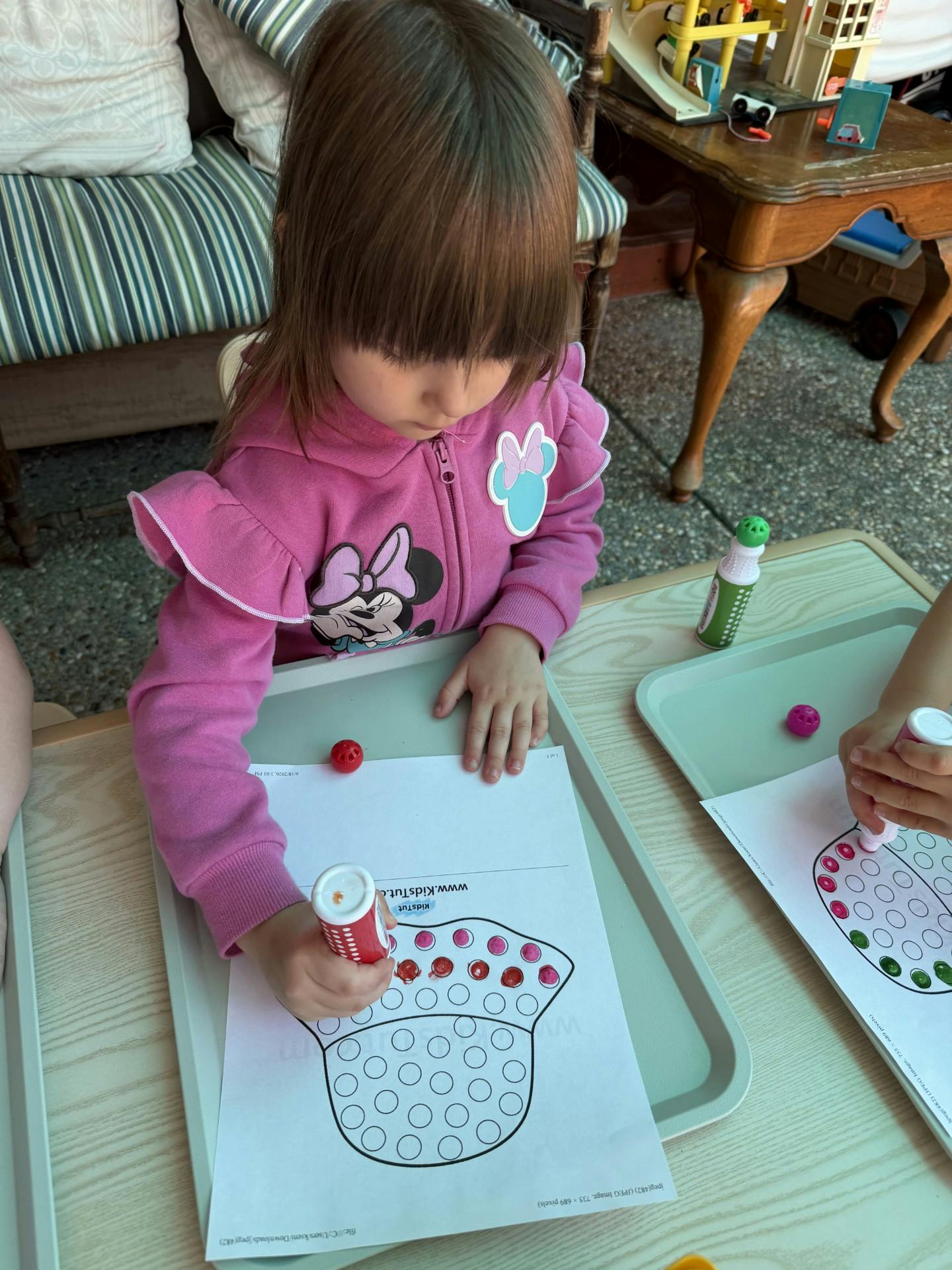 Child using a dot marker on a worksheet at a table