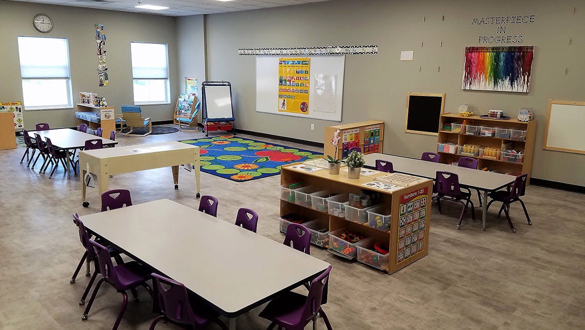 Empty classroom with tables, chairs, and learning materials