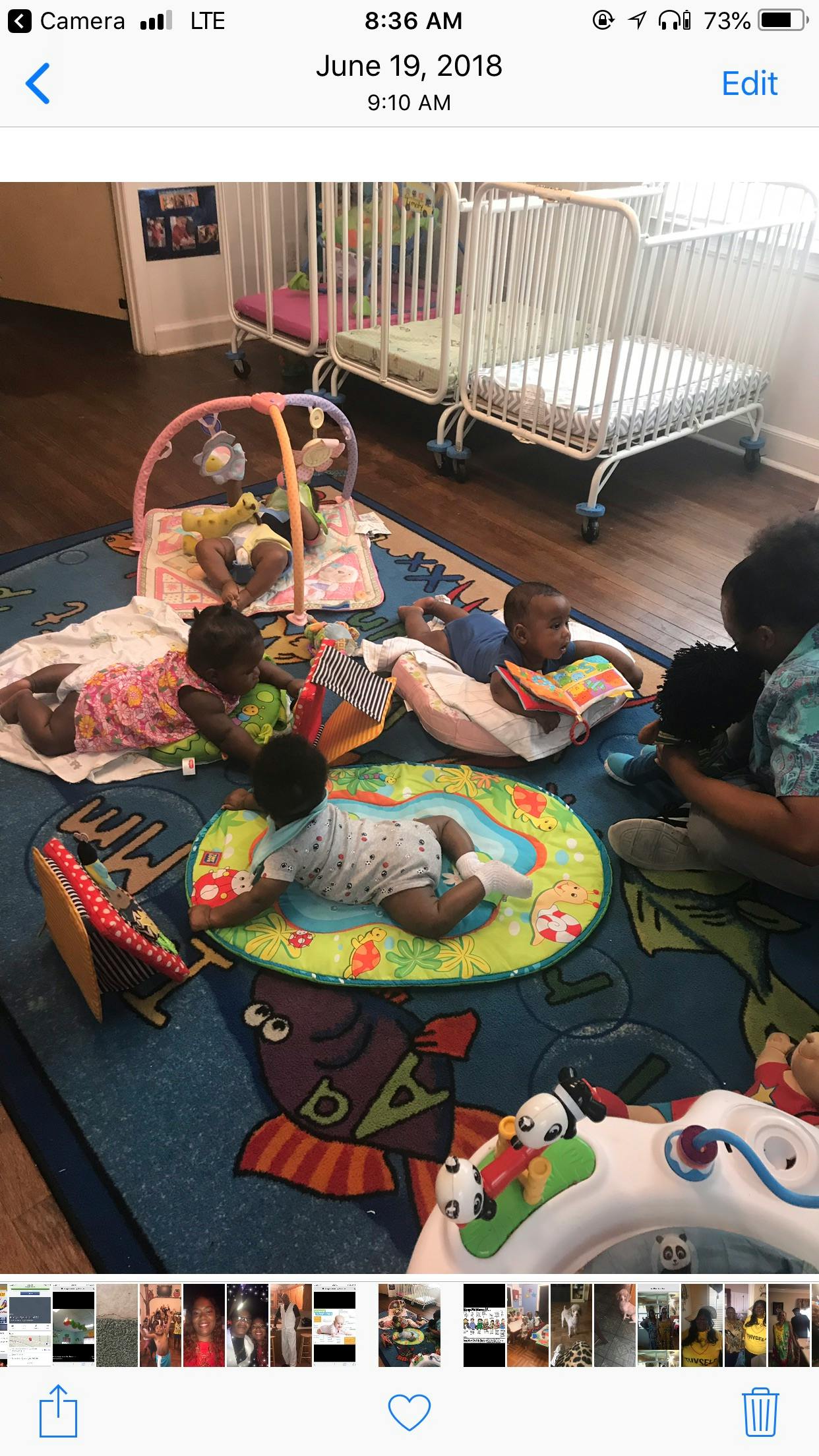Multiple babies playing on mats and a rug, with cribs in the background