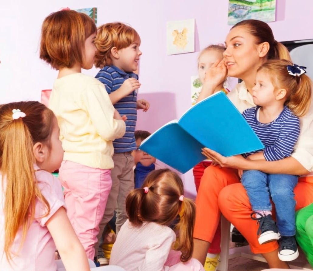 Adult reading a book to children in a classroom