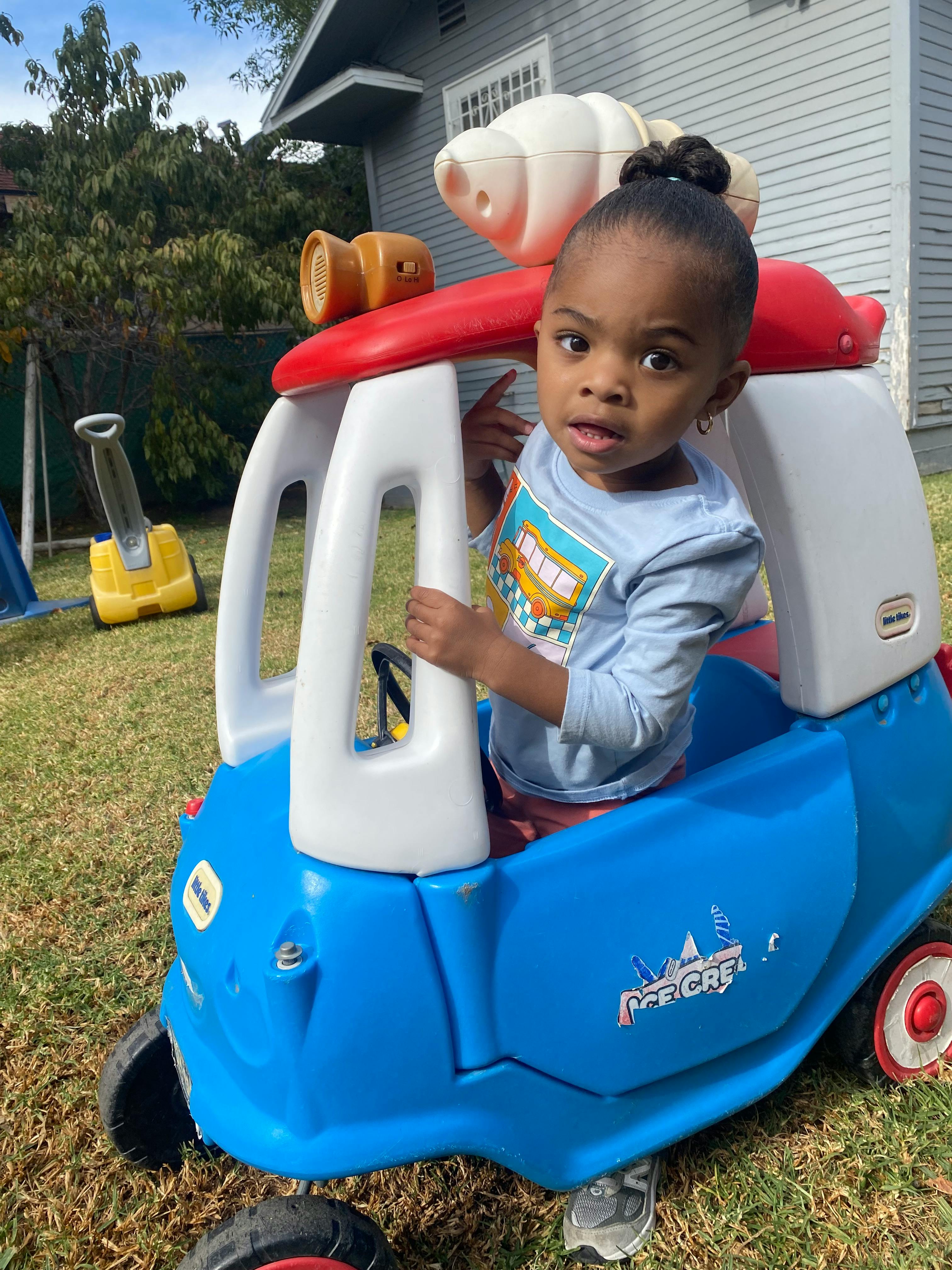 Child looking at camera while sitting in a toy car