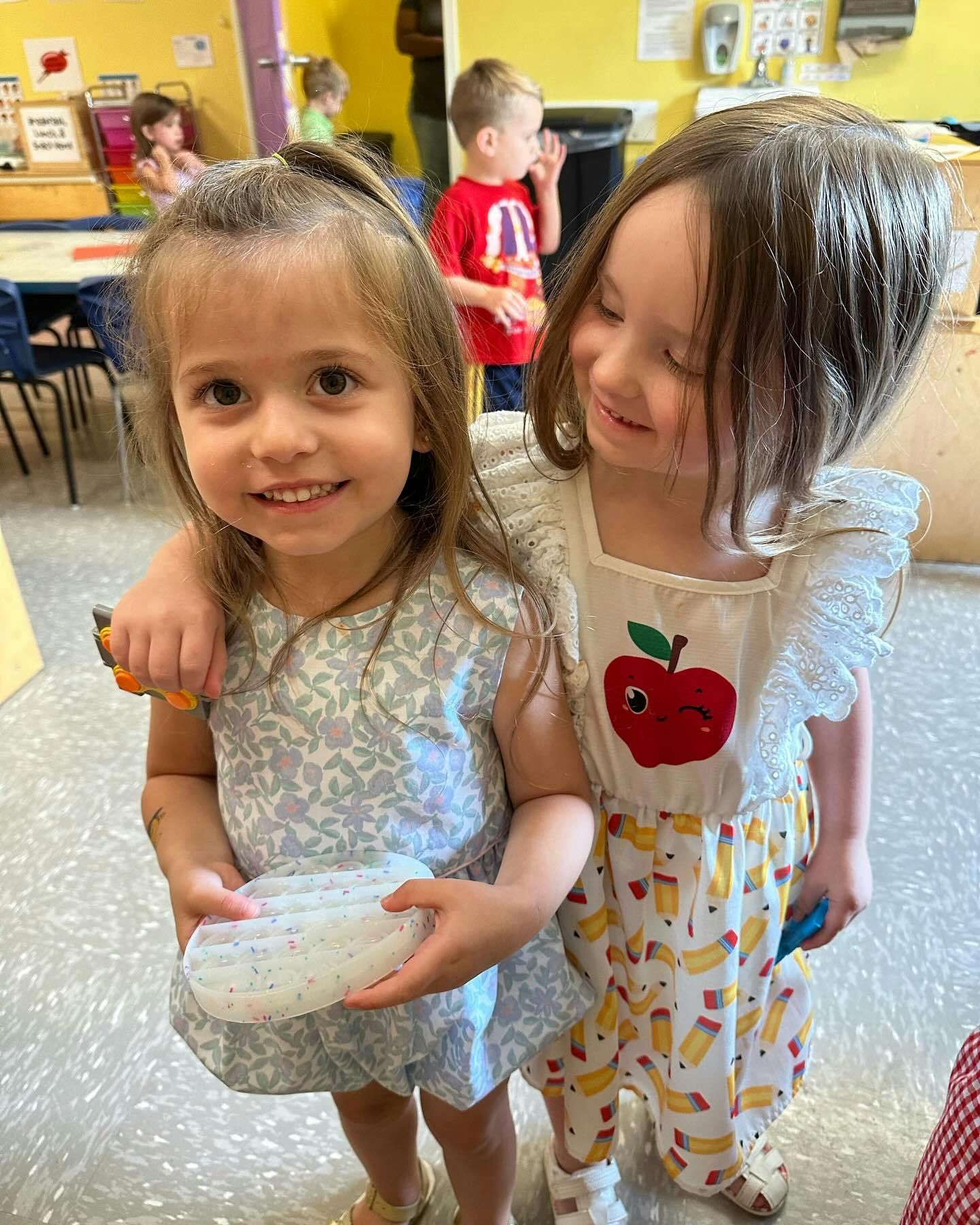 Two children standing together, one holding an object
