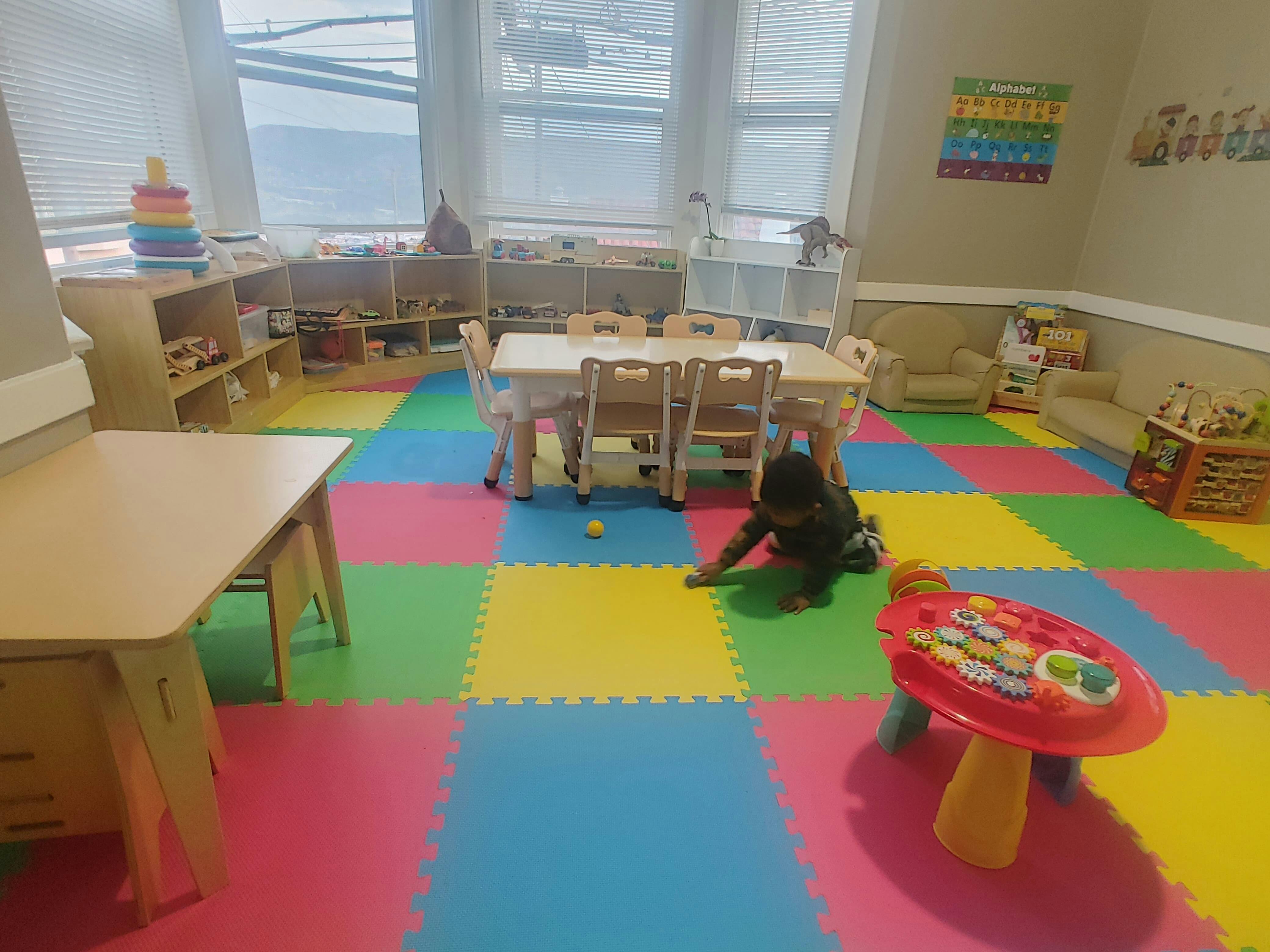 Child playing on a colorful mat in a classroom