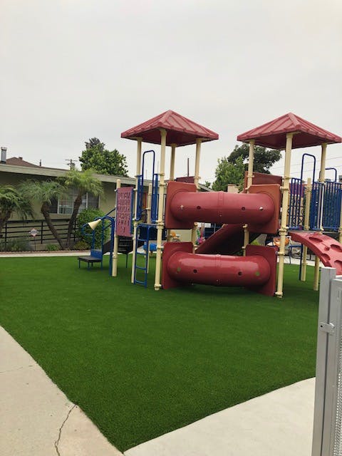 Playground with red and blue play structure on green artificial turf