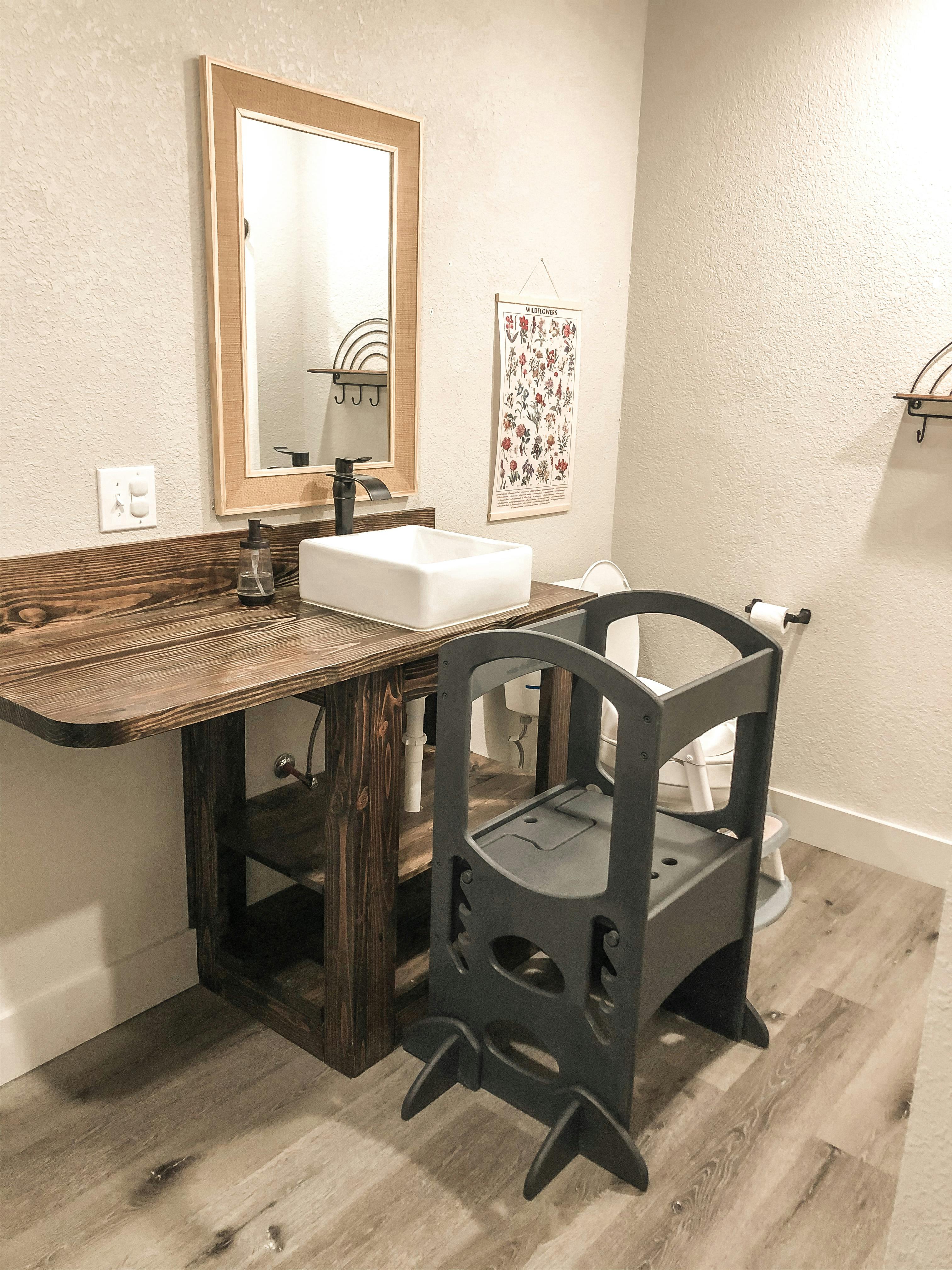 Bathroom vanity with a white sink, mirror, and a child's step stool