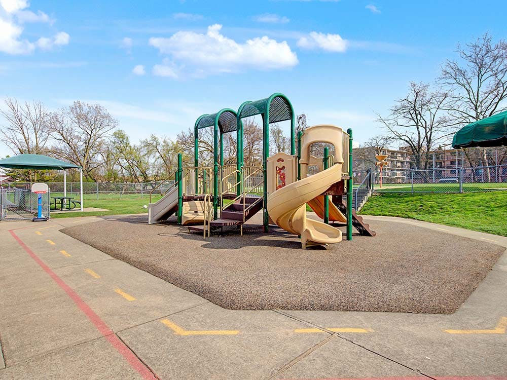 Empty playground with tan slides and green climbing structures