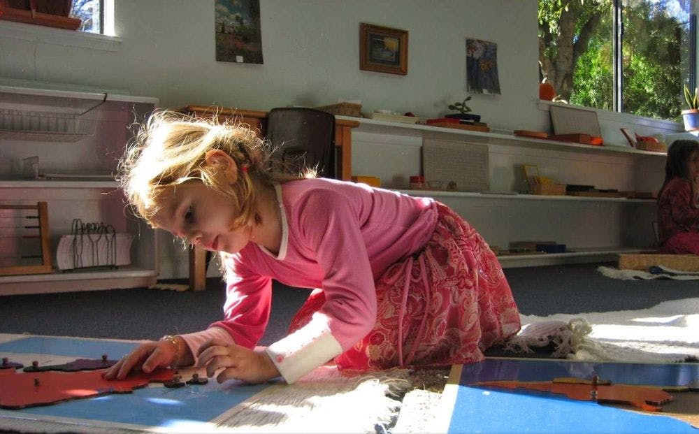 Child kneeling on floor playing with shapes inlays
