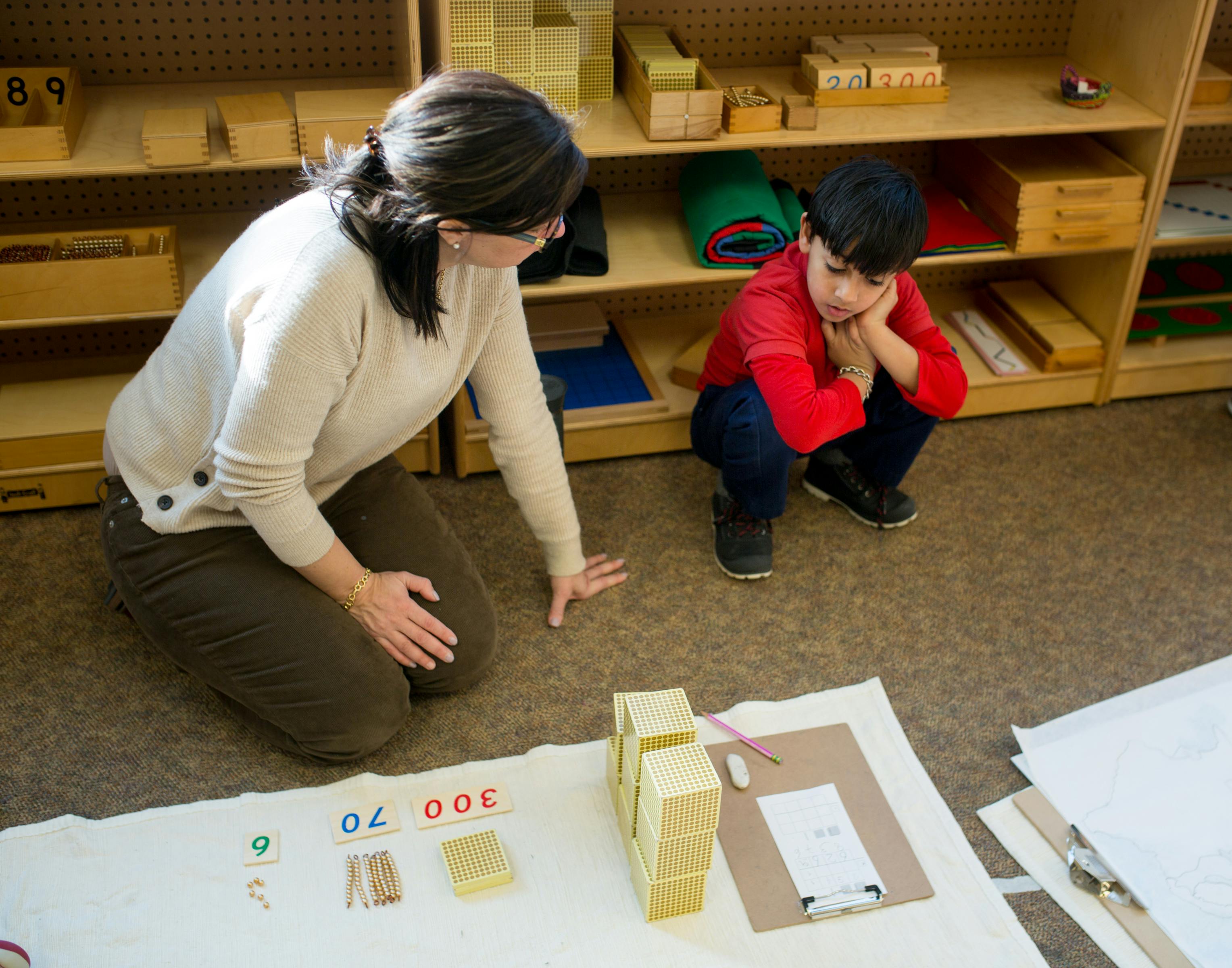 Person and child on floor with learning materials