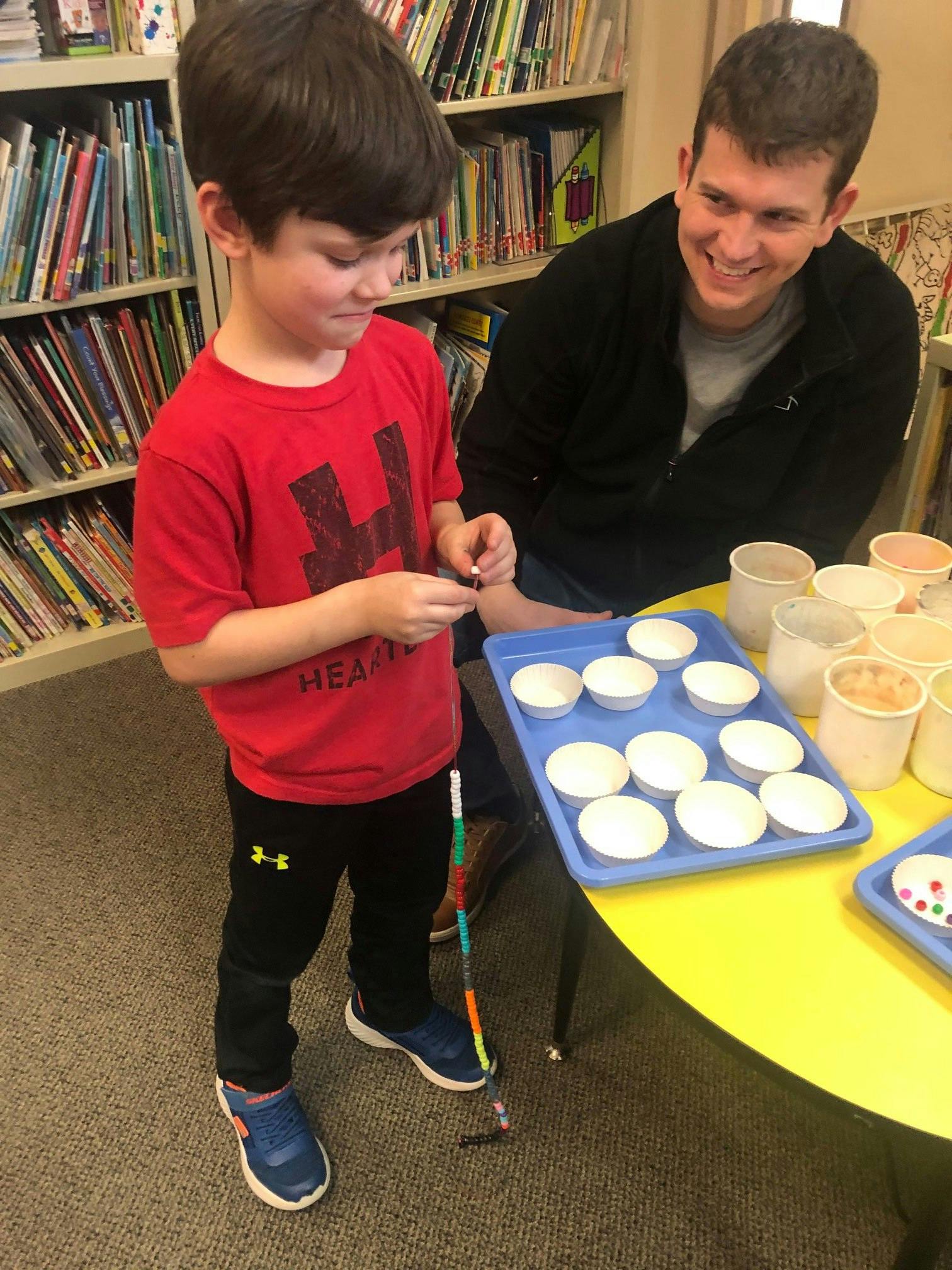 Child and person at a table with small cups and trays