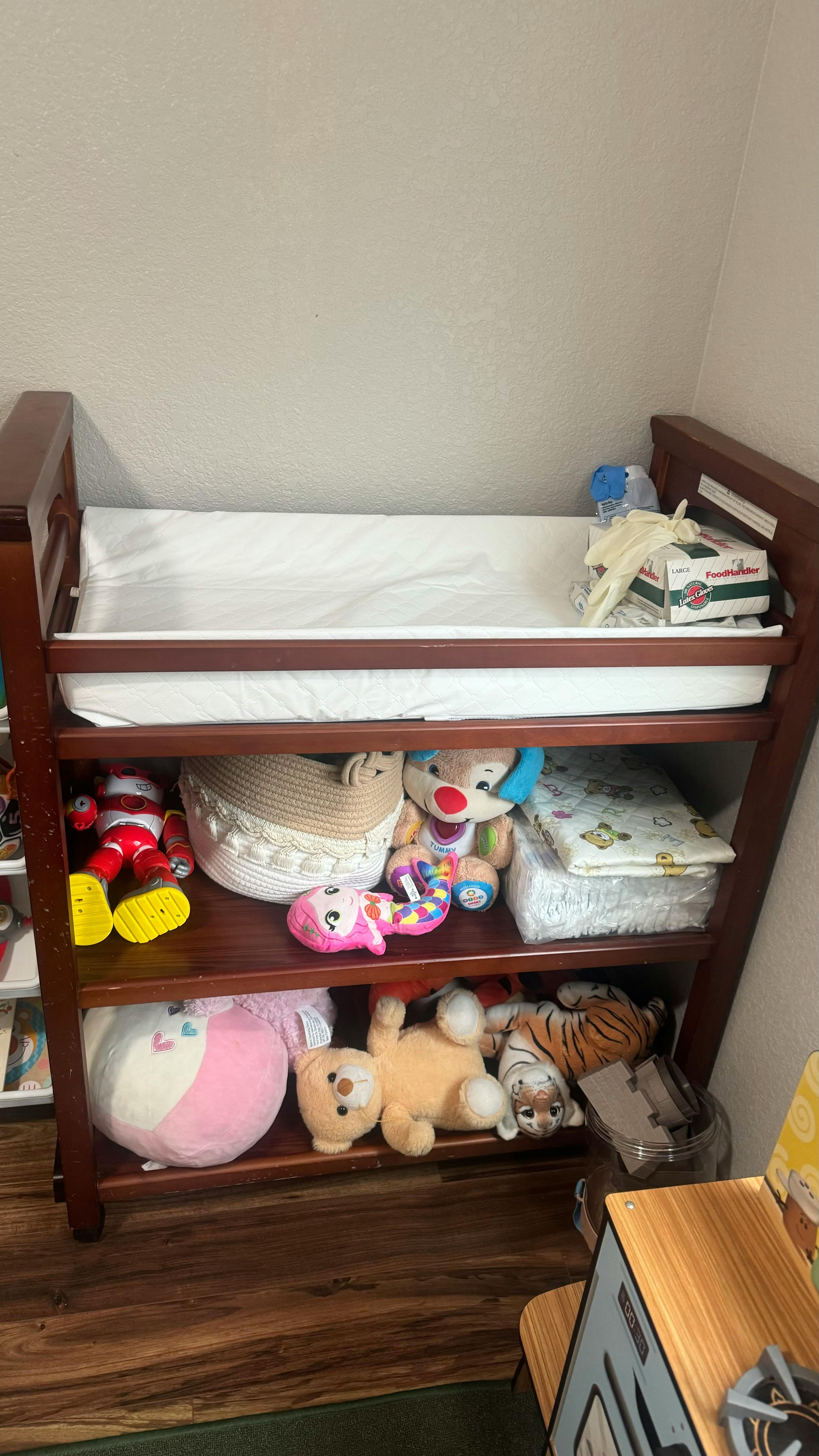 Baby changing table with shelves full of stuffed animals and baby supplies