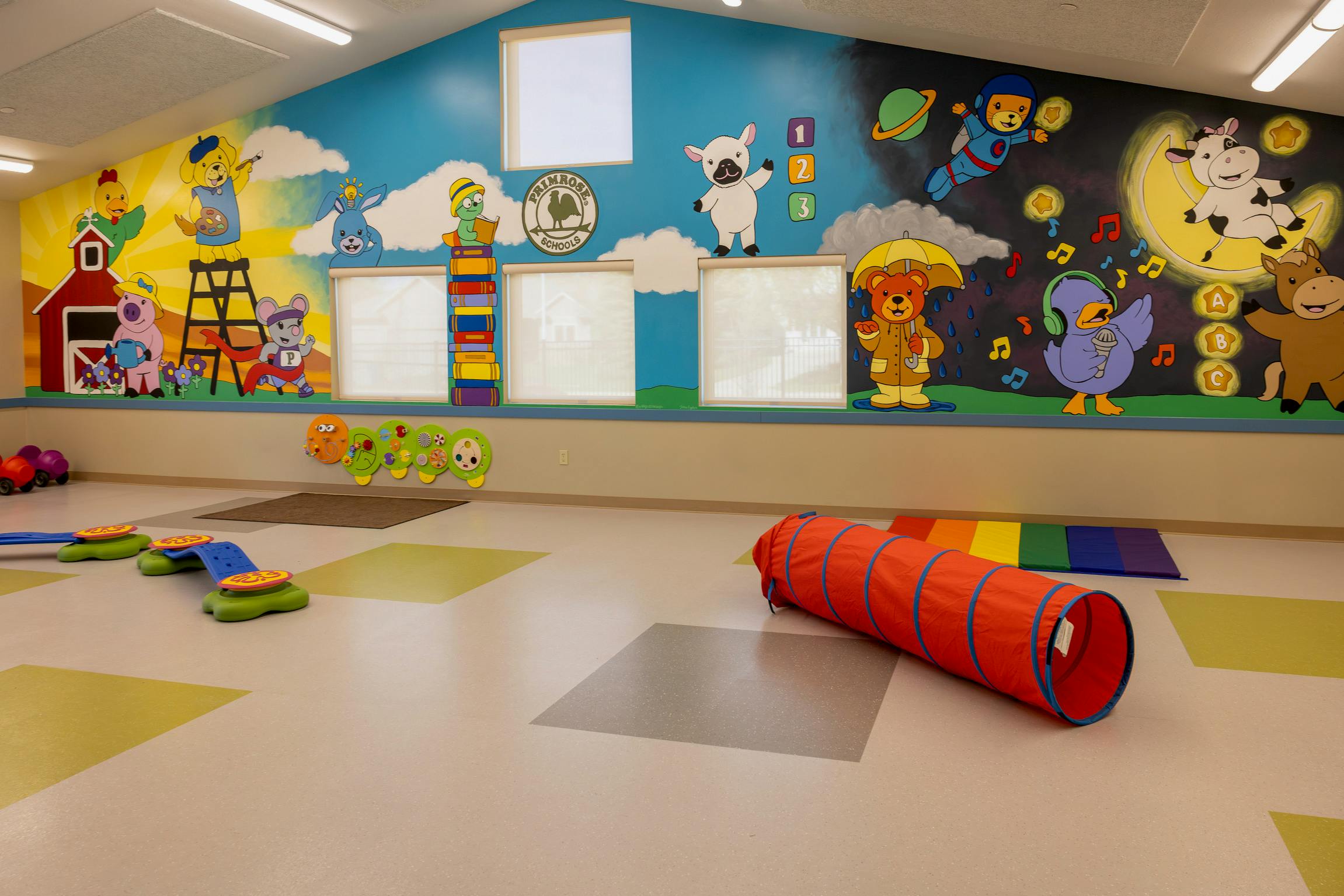 Classroom with painted cartoon animals on the wall and play equipment on the floor
