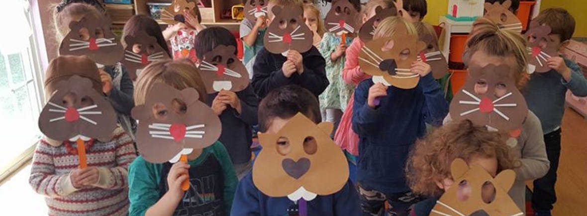 Children holding up animal masks in a classroom