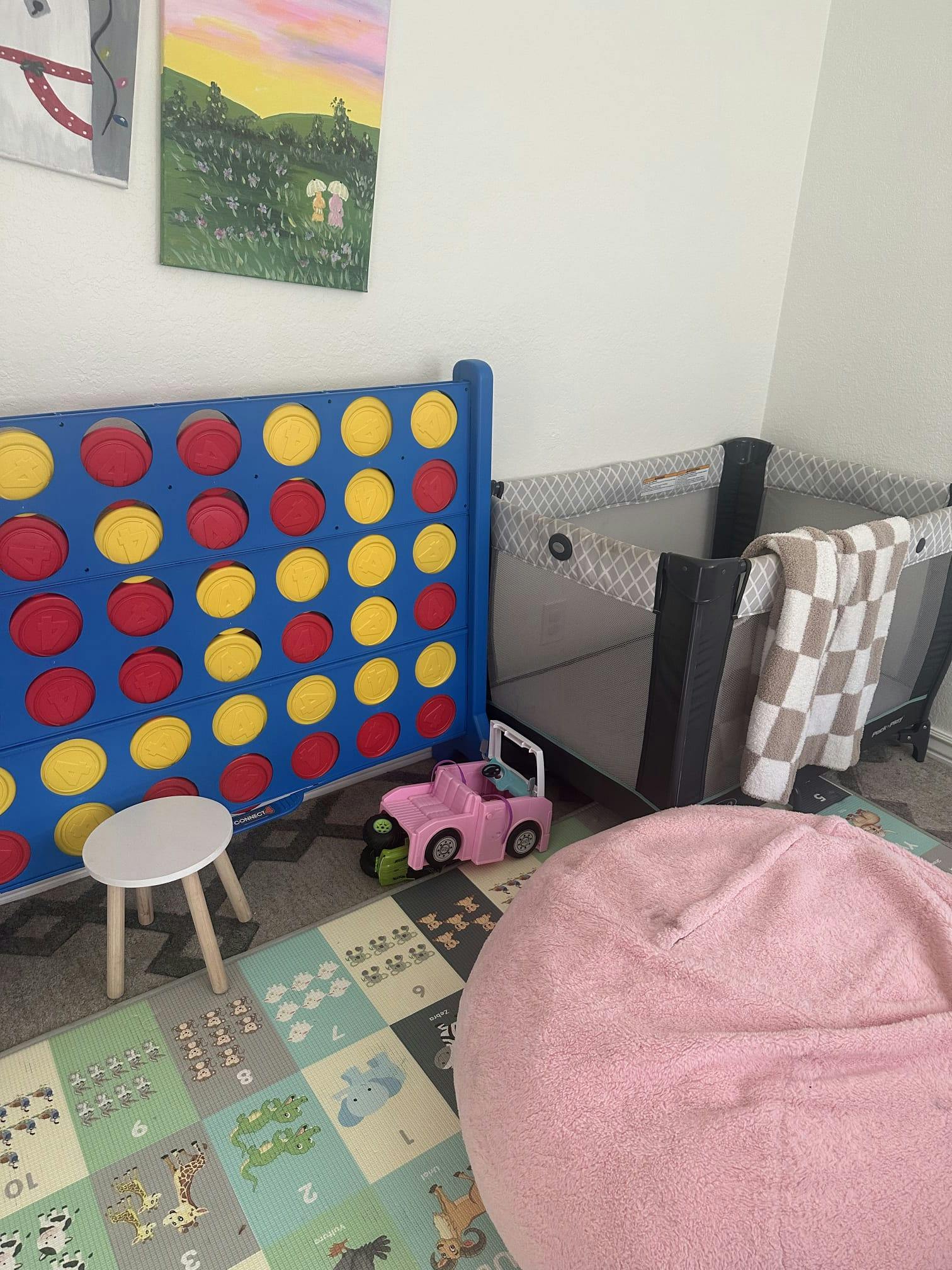 Playroom with a giant connect four game and a portable crib